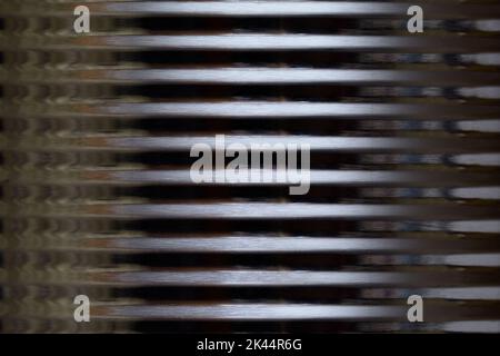 The outer side of a shiny round corrugated tin metal container with a bright, vertical central highlight creating a dramatic, cold, alien image Stock Photo