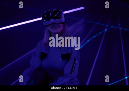 Woman is using virtual reality headset to access in metaverse. Concept of virtual, augmented and extended reality, future technology, artificial intel Stock Photo