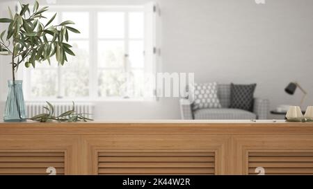 Wooden table top, cabinet, panel or shelf with shutters close up. Olive branch in vase and candles. Blurred background with white living room with arm Stock Photo