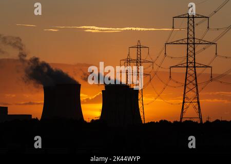 Silhouette of a power station's cooling towers against a beautiful Autumn sunset near Drax in North Yorkshire, UK, with electricity pylons and plumes Stock Photo