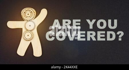 Business concept. On a black background, the figure of a man and gears, next to the inscription - ARE YOU COVERED Stock Photo