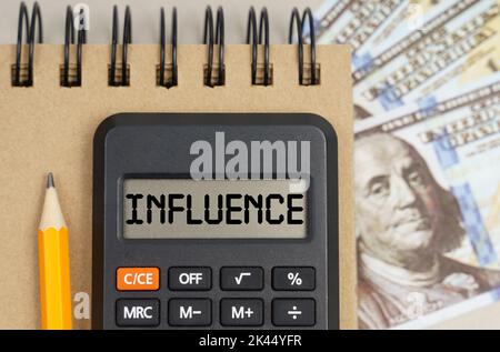 Business and finance concept. On the table there are dollars, a notebook and a calculator with the inscription - INFLUENCE Stock Photo