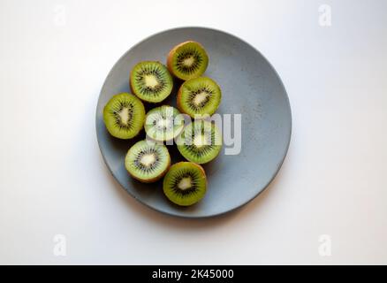 Cut kiwi fruits on grey concrete plate isolated on white background from a high angle view Stock Photo
