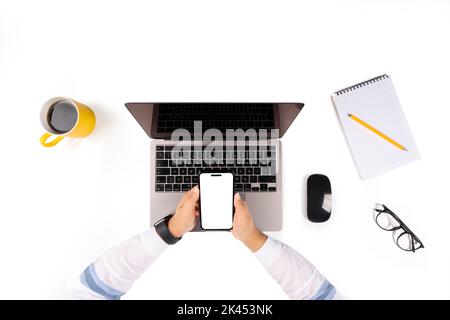 Woman working on laptop, top view photo of woman working on laptop. using smartphone for mock up. White blank screen. Business desk setup, mouse. Stock Photo