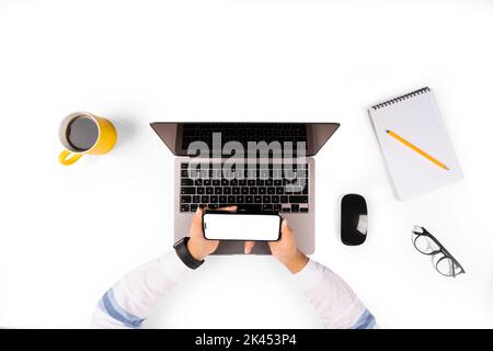 Horizontal smartphone mock up, top view of office worker holding horizontal smartphone mock up. Workplace isolated on white background. Stock Photo