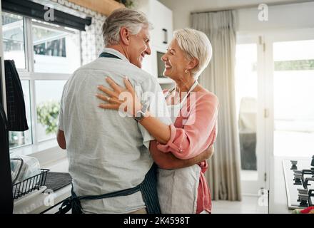 Cooking dance, dinner and senior couple dancing with smile while making lunch in the kitchen of house. Happy elderly man and woman doing jazz movement Stock Photo