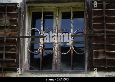 A closeup of an old window with wooden frames and rusty metal fence Stock Photo