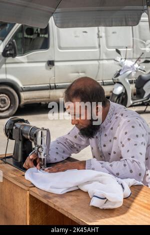 A tailor works at his outdoor stall in the daily Fera 'o Luni street market in Piazza Carlo Alberto, central Catania, Sicily, Italy Stock Photo