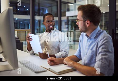 Business men, computer or planning in night office with notebook, paper or documents for programming company. Teamwork, collaboration or talking Stock Photo