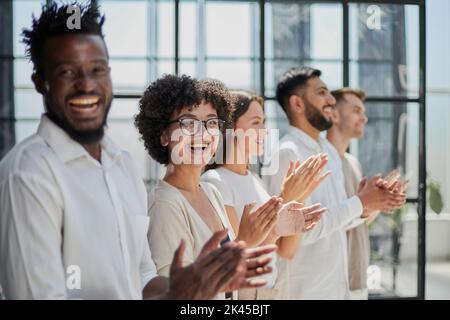 Group of businesspeople sitting in a line and applauding. Stock Photo