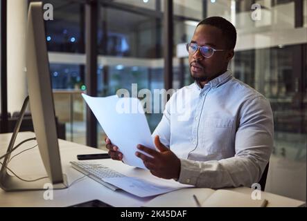 Night worker, black businessman and paperwork planning, reading documents and financial reports at desktop computer in Jamaica. Young focus Stock Photo