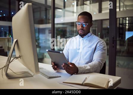 Black businessman, tablet planning and desktop at night in startup for online ideas, strategy and connect apps on 5g technology in Nigeria. Employee Stock Photo