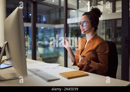 Call center, customer support and insurance agent consulting at night in a office at a contact help desk. Sales, telemarketing and employee working Stock Photo