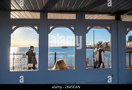 Visitors enjoy walking along Brighton Palace Pier on a late Autumn afternoon in sunshine , Sussex , England UK Stock Photo