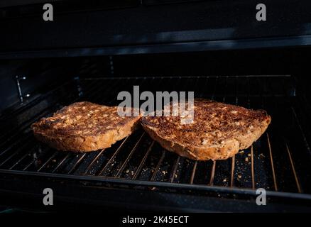 Making toast with brown granary bread under an electric grill in kitchen Stock Photo