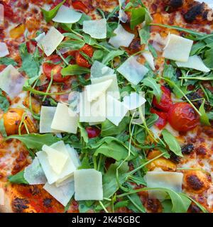 Vegetarian pizza with fresh ingredients: tomatoes, rucola salad, Parmesan cheese. Baked in a stone oven. Stock Photo