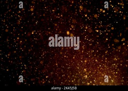 Natural organic golden dust particles floating on black background. Glittering sparkling flickering glowing. Stock Photo