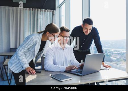 Group of business people in casual clothes talking to each other in office and using gadgets while working on business startup in modern workspace Stock Photo