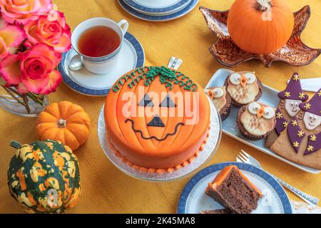 Tea time table set with novelty cakes decorated in Halloween theme. Stock Photo