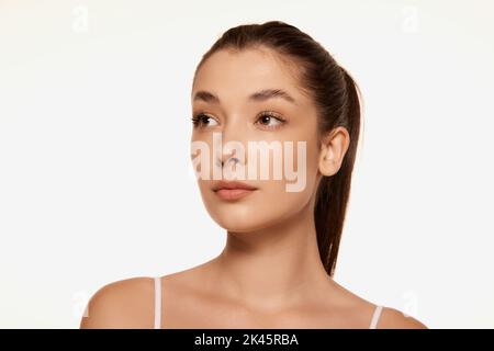 Portrait of young beautiful woman with clear spotless skin isolated over white background. Lifting effect Stock Photo