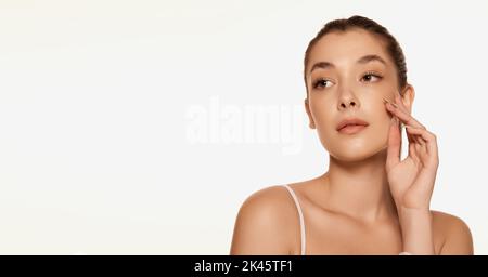 Portrait of young beautiful woman with clear spotless skin isolated over white background. Face care with cosmetics Stock Photo