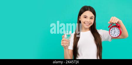 happy kid hold glass of water and clock to stay hydrated and keep daily water balance, thirst. Banner of child girl with glass of water, studio Stock Photo