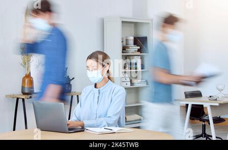 Business woman, busy office and covid compliance while on laptop and blur of people around her. Employees in the office during coronavirus wearing Stock Photo