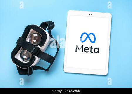 April, 2022, Canada. White tablet with Meta logo screen on digital display, vr glasses for virtual reality games on blue background Rebranding of social media Facebook. Stock Photo