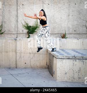 Sequence of Shots of Happy Young Black Woman Jumping Off a Walkway Stock Photo