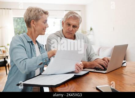 Senior couple, laptop and home finance while reading paperwork documents and typing on computer for retirement savings, mortgage and online banking Stock Photo