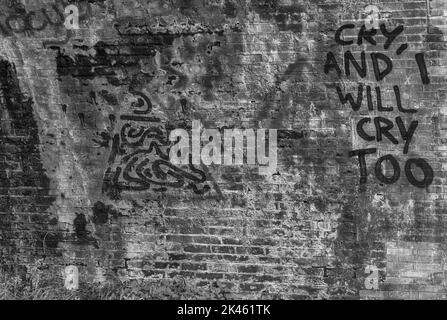 Graffiti offering to cry with you, painted on the brck wall of a railway arch. Stock Photo