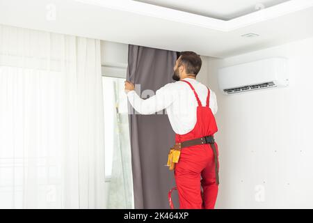 Man hanging window curtain indoors. Interior decor element Stock Photo