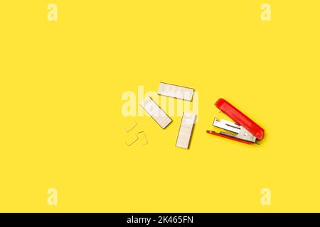 A paper stapler and staples on a yellow background with copy space Stock Photo