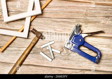 A blue stapler gun, staples and photo frames on a wooden table Stock Photo