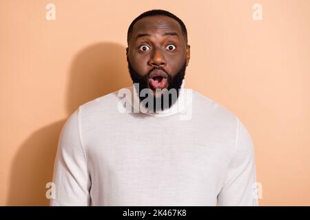 Photo of funky impressed young guy dressed white pullover big eyes isolated beige color background Stock Photo