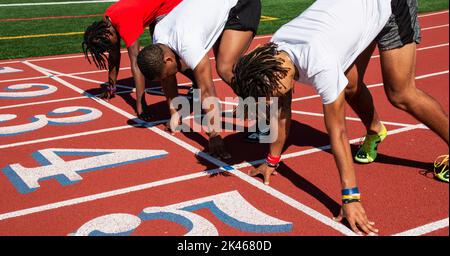 West Islip, New York, USA - 25 May 2022: Three high school sprinter are in the set position ready to race at practice getting ready for the state cham Stock Photo