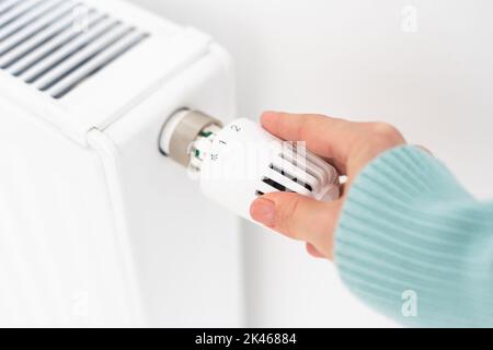 Woman's hand on a white radiator. Heating season. Energy crisis. Cold batteries. Central heating Stock Photo