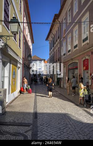 Aveiro, Portugal - August 14, 2022: Narrow street scene with numerous motion blurred pedestrians on cobble-stoned road Stock Photo