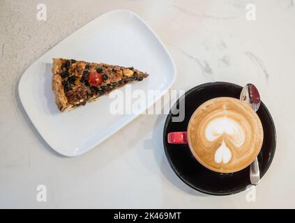 A slice of Ecclefechan Tart on a white plate with a cup of coffee Stock Photo