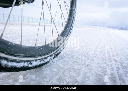close up of bicycle wheel on white icy road. Cycling in extreme winter conditions concept and winter tyres Stock Photo