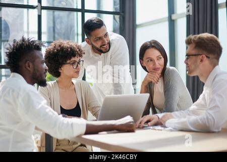 Employees working at computer together, discussing content Stock Photo