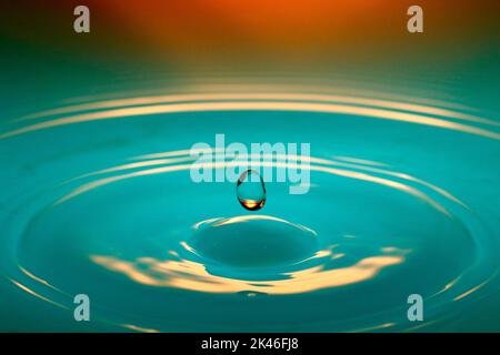 A floating drop above colored liquid Stock Photo - Alamy