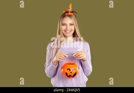 Beautiful woman holding Jack-o-pumpkin basket to collect candy trick or treat on Halloween day. Stock Photo