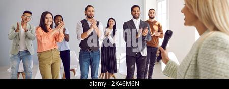 Satisfied happy multiracial audience at business seminar applauds successful female speaker. Stock Photo