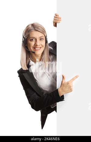 Young female call operator standing behind a blank white board and pointing isolated on white background Stock Photo