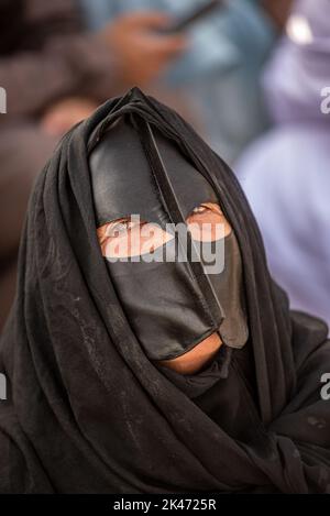 Woman with black 'battoulah' (face mask) at friday morning cattle market, Nizwa, Oman Stock Photo