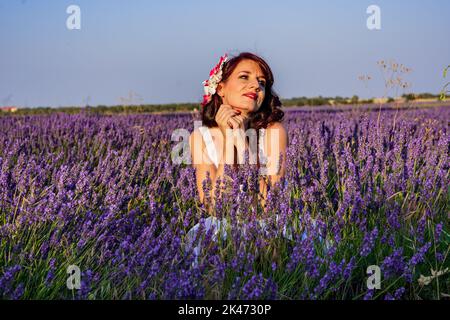 Stylish woman looking away while posing outdoors in a colourful lavender field. Nature concept. Stock Photo
