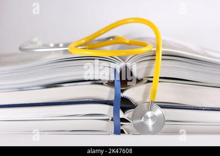 stethoscope and stack of opened books isolated on white background. Medical professional education and information concept. Stock Photo