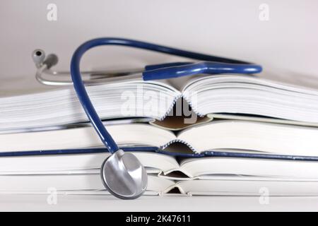 stethoscope and stack of opened books isolated on white background. Medical professional education and information concept. Stock Photo