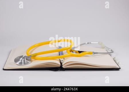 A medical stethoscope with a yellow heart on an open notebook with a blue pen for medical concept Stock Photo